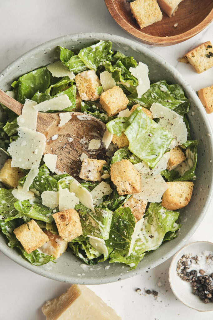Classic Caesar salad with crisp romaine lettuce, creamy dressing, crunchy croutons, and freshly grated Parmesan cheese, served in a light, airy setting.