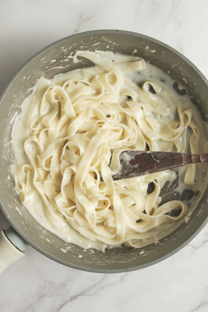 Creamy fettuccine Alfredo in a pan, coated in a silky butter and Parmesan sauce with freshly ground black pepper.
