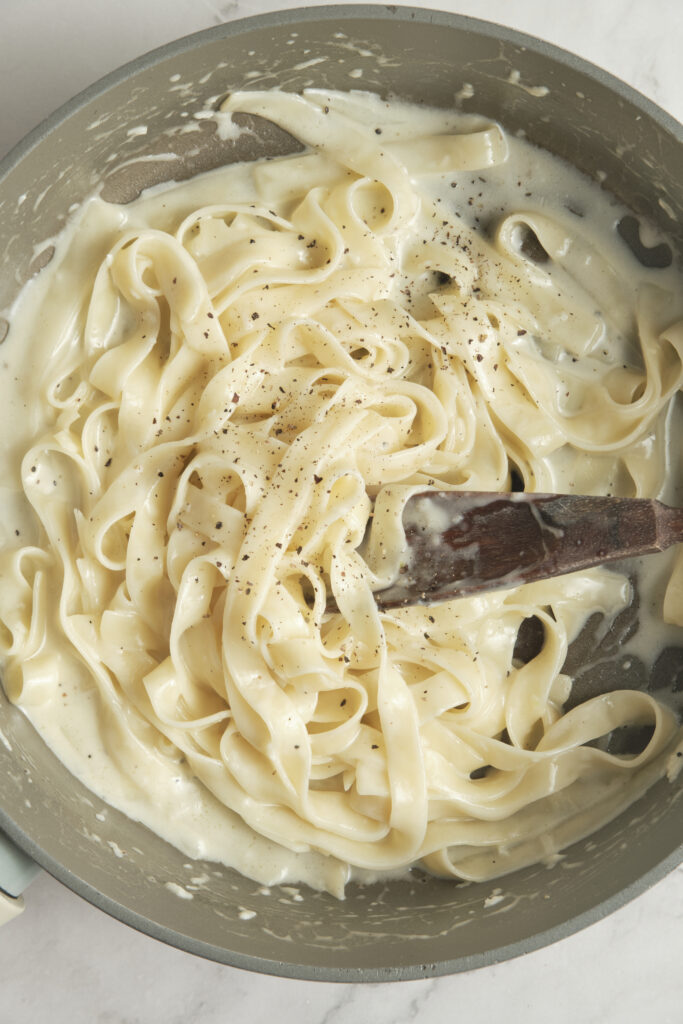 Creamy fettuccine Alfredo in a pan, coated in a silky butter and Parmesan sauce with freshly ground black pepper.
