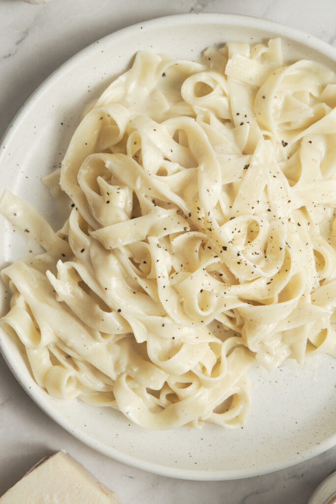 Creamy fettuccine Alfredo in a pan, coated in a silky butter and Parmesan sauce with freshly ground black pepper.