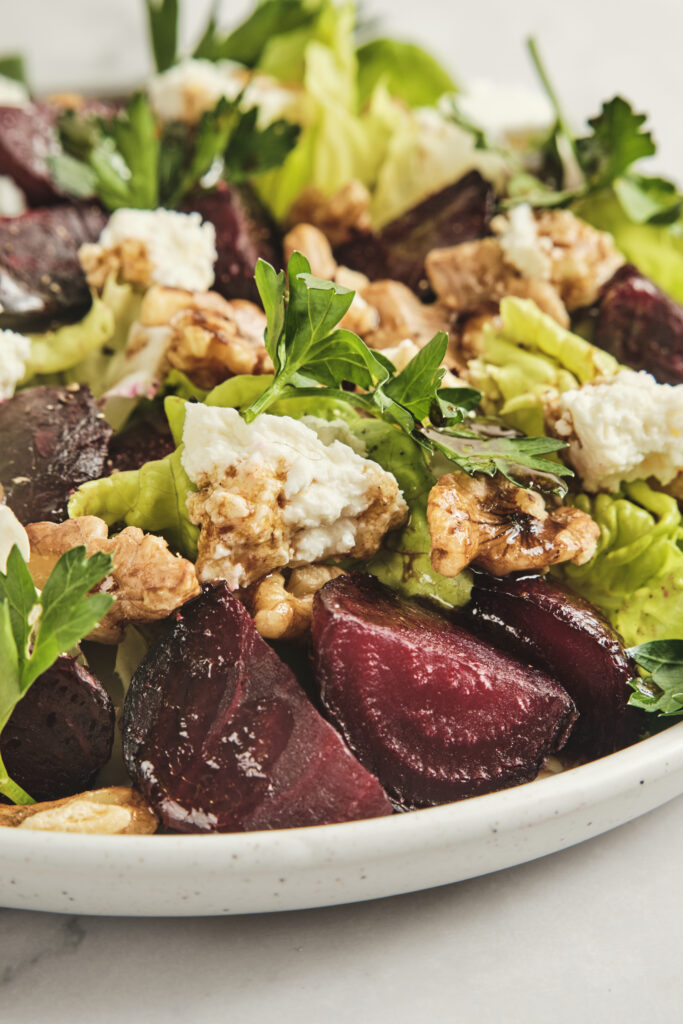 Close-up of roasted beets with walnuts and soft cheese.
