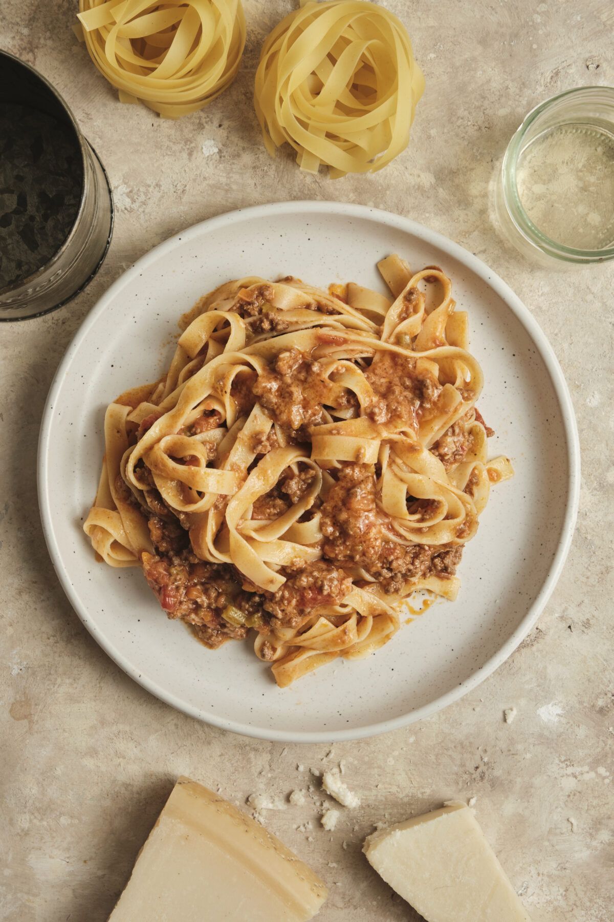 Authentic Beef Bolognese serve with fresh Tagliatelle Pasta and topped with grated Parmesan Cheese, plated on a white plate