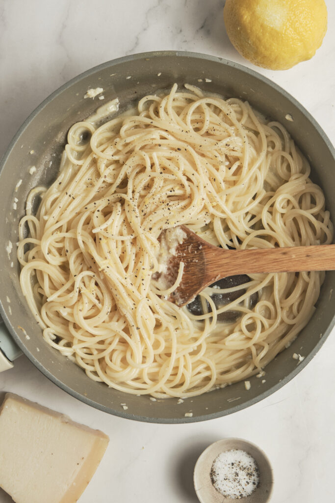 Creamy lemon pasta garnished with grated Parmesan in a skillet.