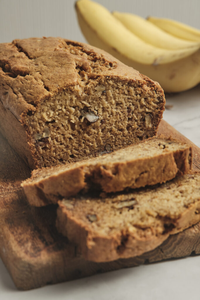 Homemade banana bread cut into slices on a wooden board.