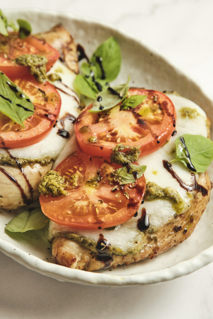 Close-up of caprese chicken with melted cheese and basil