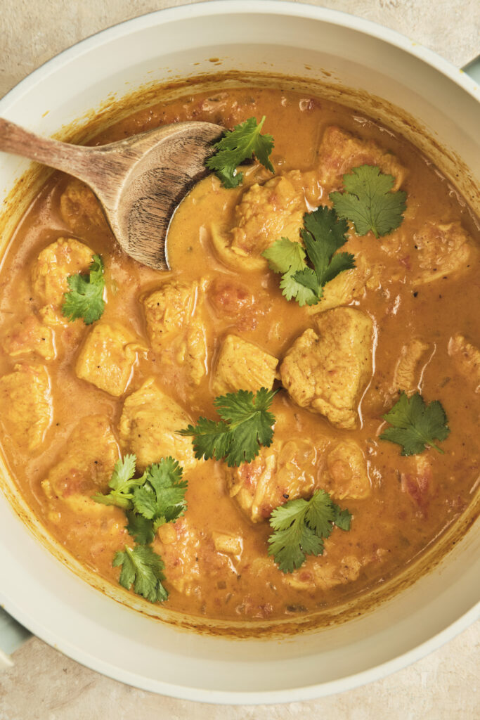 Creamy coconut chicken curry served in a bowl with fresh herbs and rice