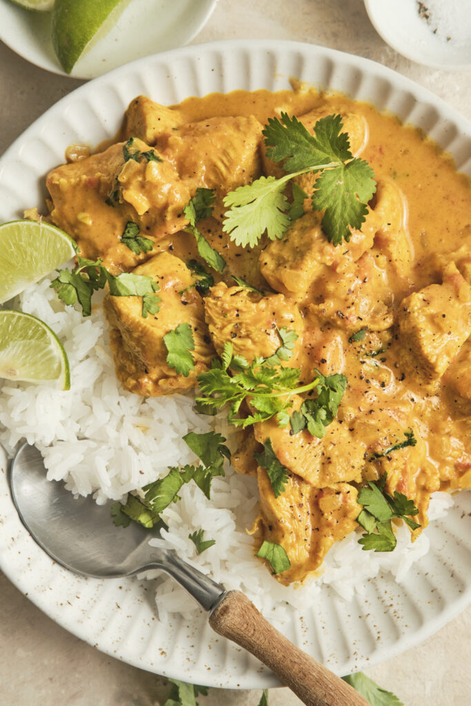 Creamy coconut chicken curry served in a bowl with fresh herbs and rice