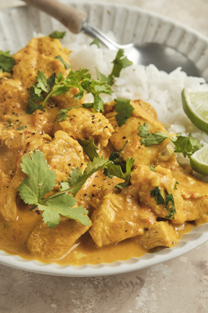 Creamy coconut chicken curry served in a bowl with fresh herbs and rice
