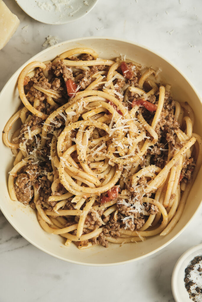 Close-up of sausage ragù pasta tossed in a rich tomato sauce, finished with fresh herbs and grated cheese—an inviting choice for sausage pasta recipes, comforting pasta dinners, and quick dinner ideas.