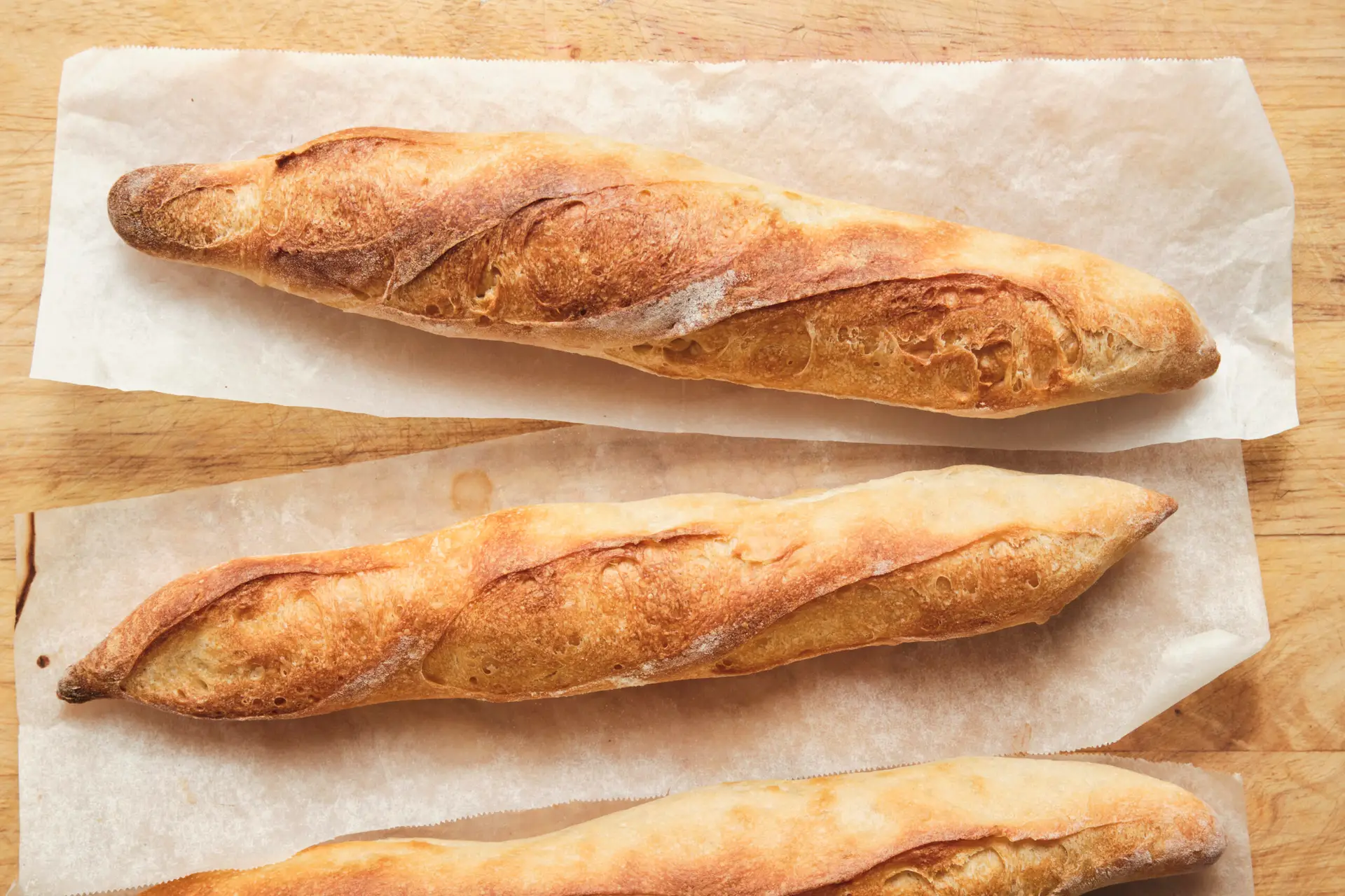 Golden brown freshly baked French baguettes straight from the oven with a crisp crust and airy interior—classic homemade baguette recipe results for how to make baguette.
