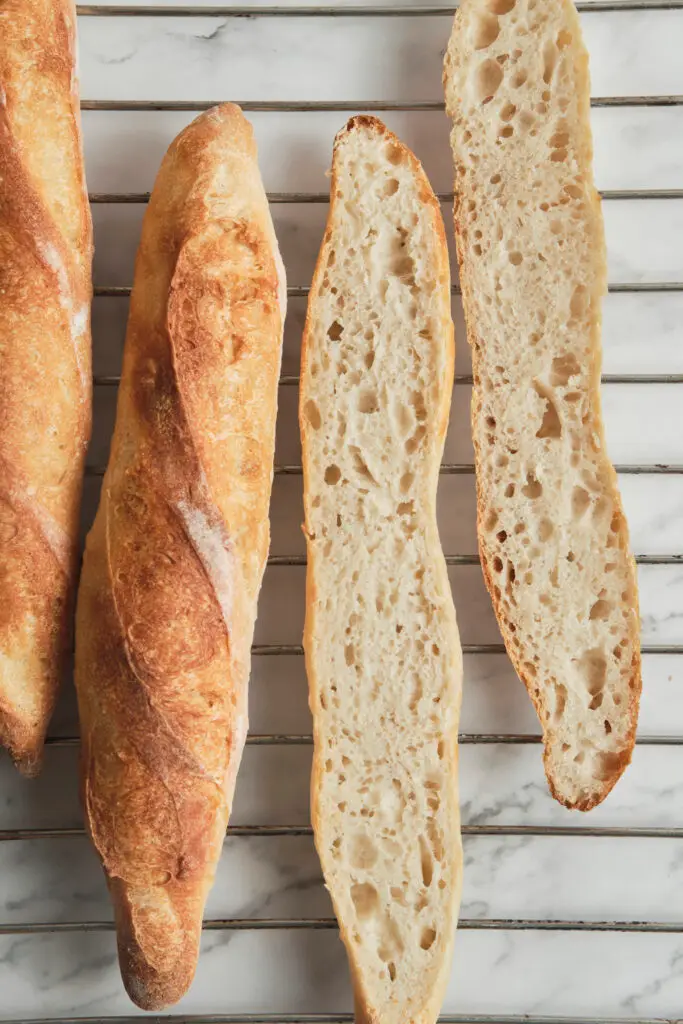 Golden brown freshly baked French baguettes straight from the oven with a crisp crust and airy interior—classic homemade baguette recipe results for how to make baguette.