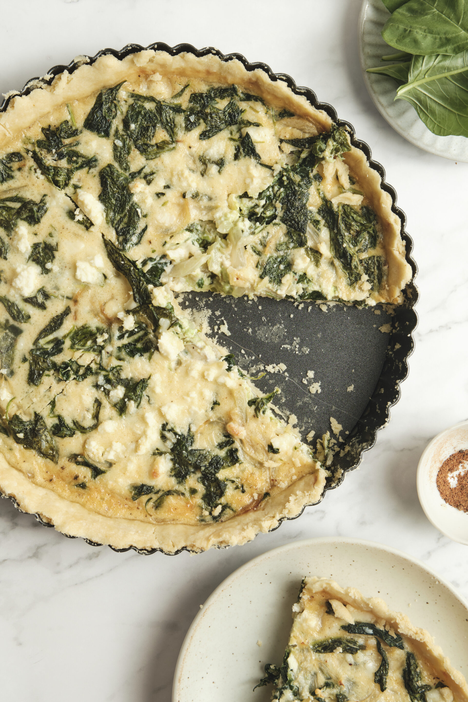 Baked spinach feta quiche with a golden crust and a sliced piece showing creamy filling—an easy spinach and feta quiche recipe perfect for vegetarian meals and simple quiche ideas.