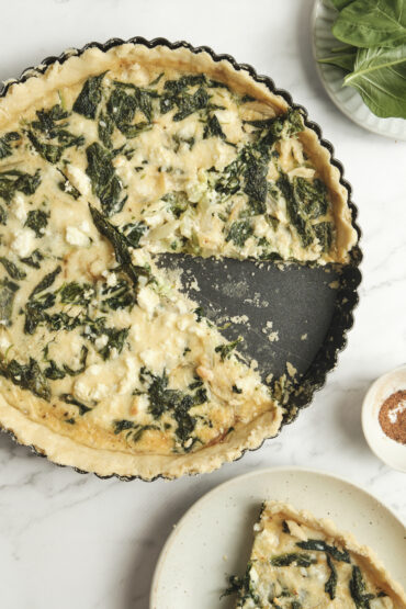 Baked spinach feta quiche with a golden crust and a sliced piece showing creamy filling—an easy spinach and feta quiche recipe perfect for vegetarian meals and simple quiche ideas.