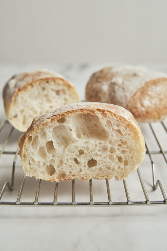 Homemade ciabatta bread sliced in half, showing a fluffy airy crumb, crispy golden crust, and soft artisan Italian bread texture.