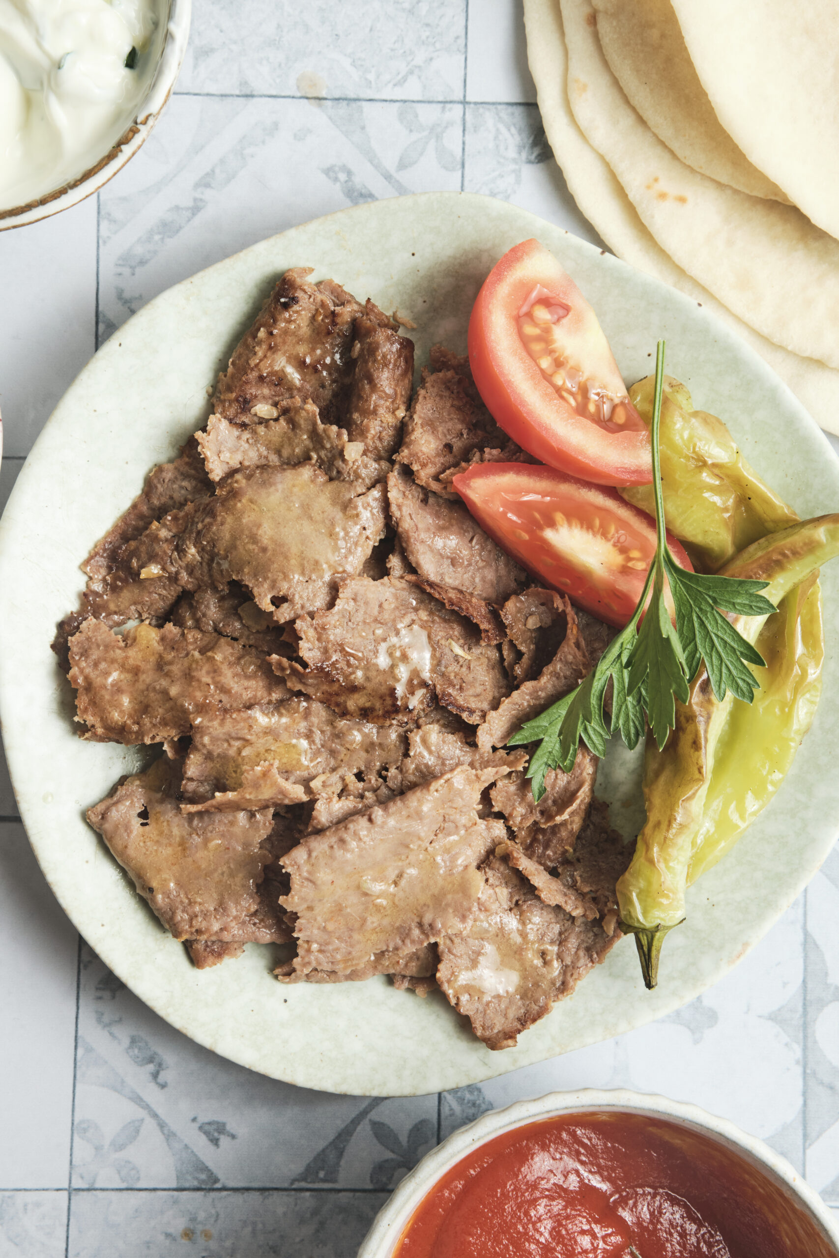 Doner kebab meat served on a plate with roasted vegetables and soft lavash bread, a homemade Turkish-style meal.