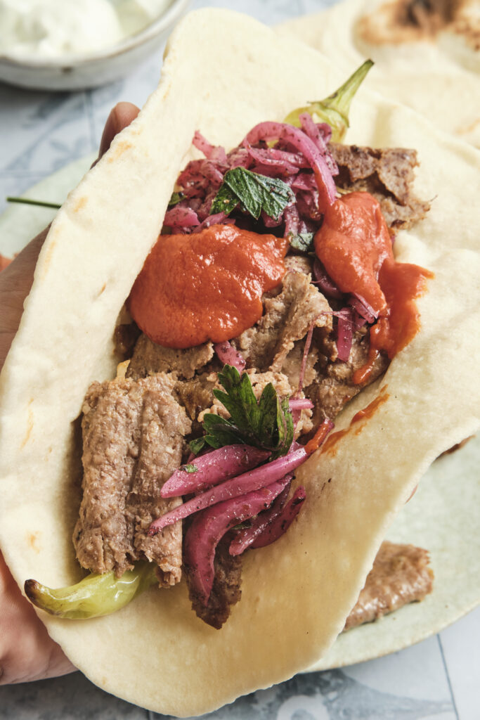 Doner kebab meat served on lavash bread with roasted vegetables, a homemade Turkish-style meal.