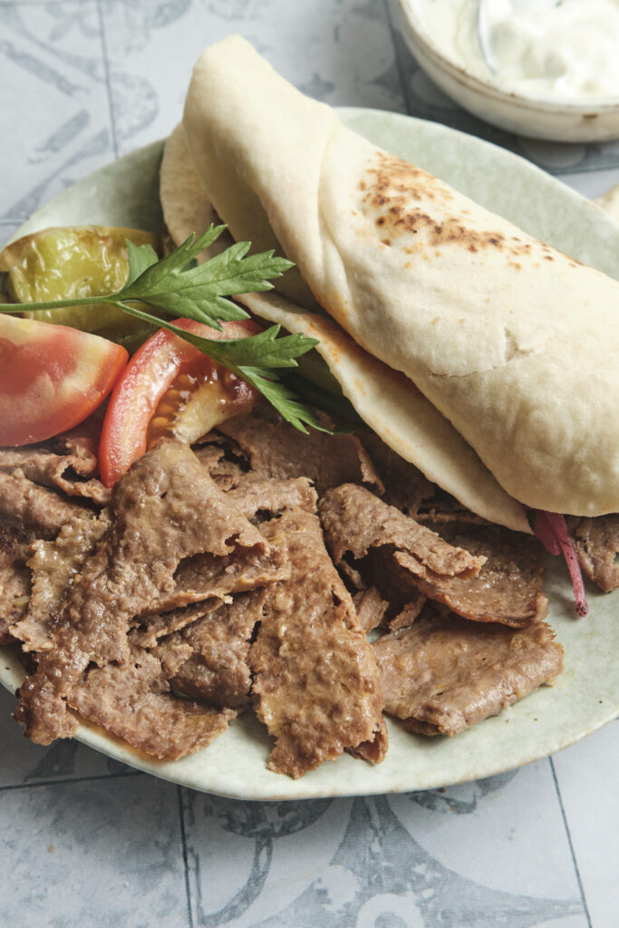 Homemade Turkish-style doner kebab served with charred vegetables and freshly baked lavash bread on a plate, ready to enjoy.