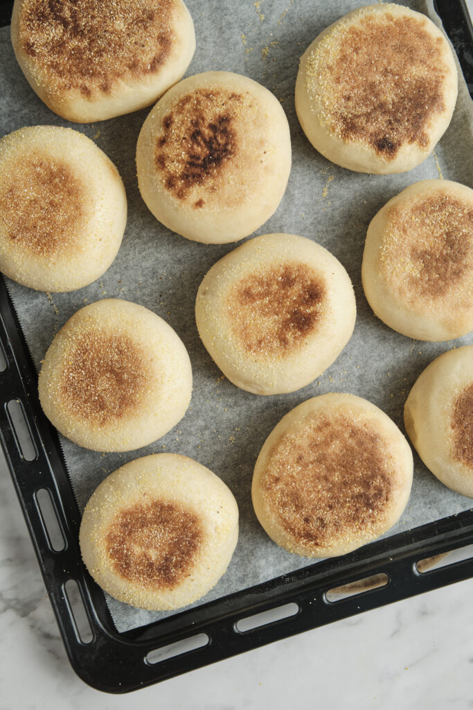 Freshly baked homemade muffins on a baking tray with golden tops and soft fluffy centers, ready to cool and serve.
