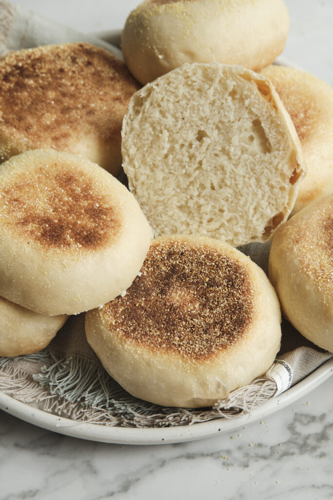 Freshly baked homemade muffins served on a plate, with one muffin cut open to reveal a soft, fluffy interior and tender crumb.