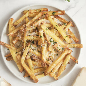 Crispy garlic parmesan french fries made in the air fryer, topped with fresh parsley and parmesan cheese, served as an easy side dish or dinner recipe.
