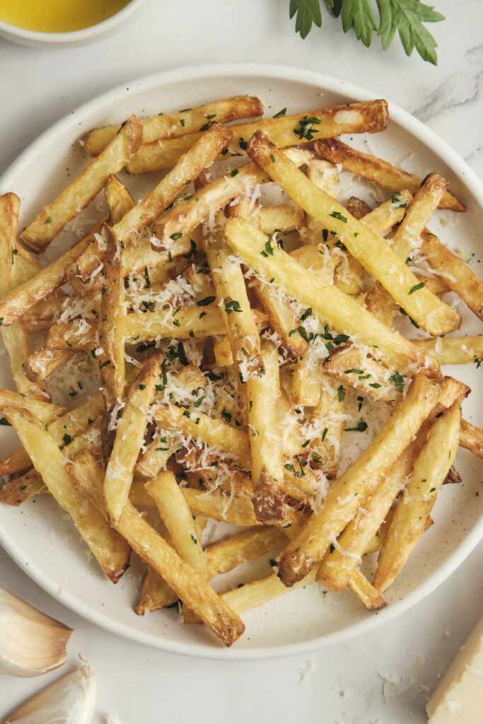 Crispy garlic parmesan french fries served on a plate, made in the air fryer and topped with grated parmesan cheese and herbs, perfect as an easy side dish or snack.