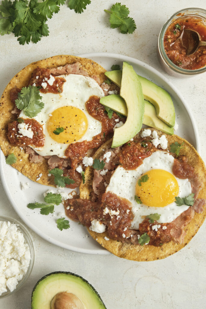 Authentic huevos rancheros topped with homemade ranchero sauce, fried eggs, and fresh cilantro, served as a classic Mexican breakfast with bold smoky flavors.