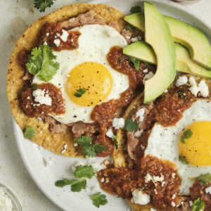 Authentic huevos rancheros topped with homemade ranchero sauce, fried eggs, and fresh cilantro, served as a classic Mexican breakfast with bold smoky flavors.
