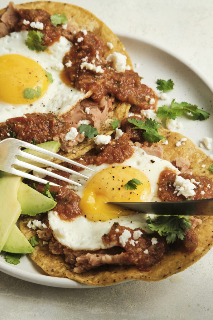 Authentic huevos rancheros topped with homemade ranchero sauce, fried eggs, and fresh cilantro, served as a classic Mexican breakfast with bold smoky flavors.