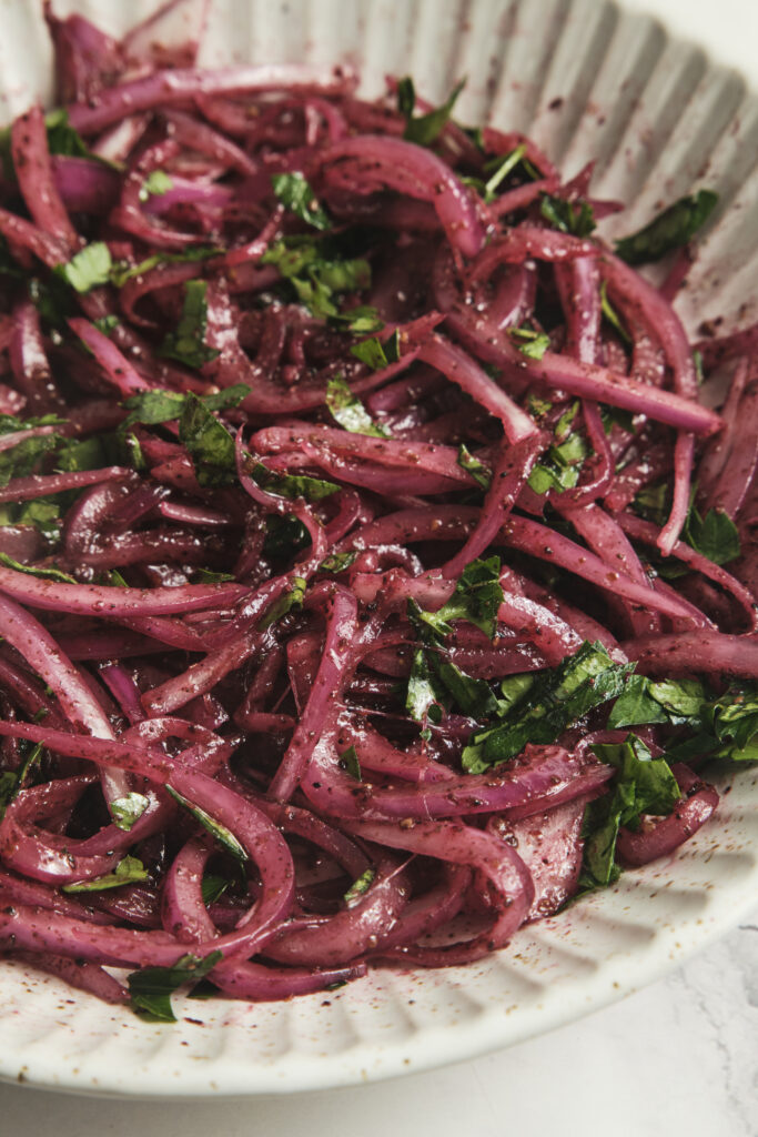 Fresh sumac onions made with thinly sliced red onions and sumac in a bowl—easy Middle Eastern red onion salad recipe.