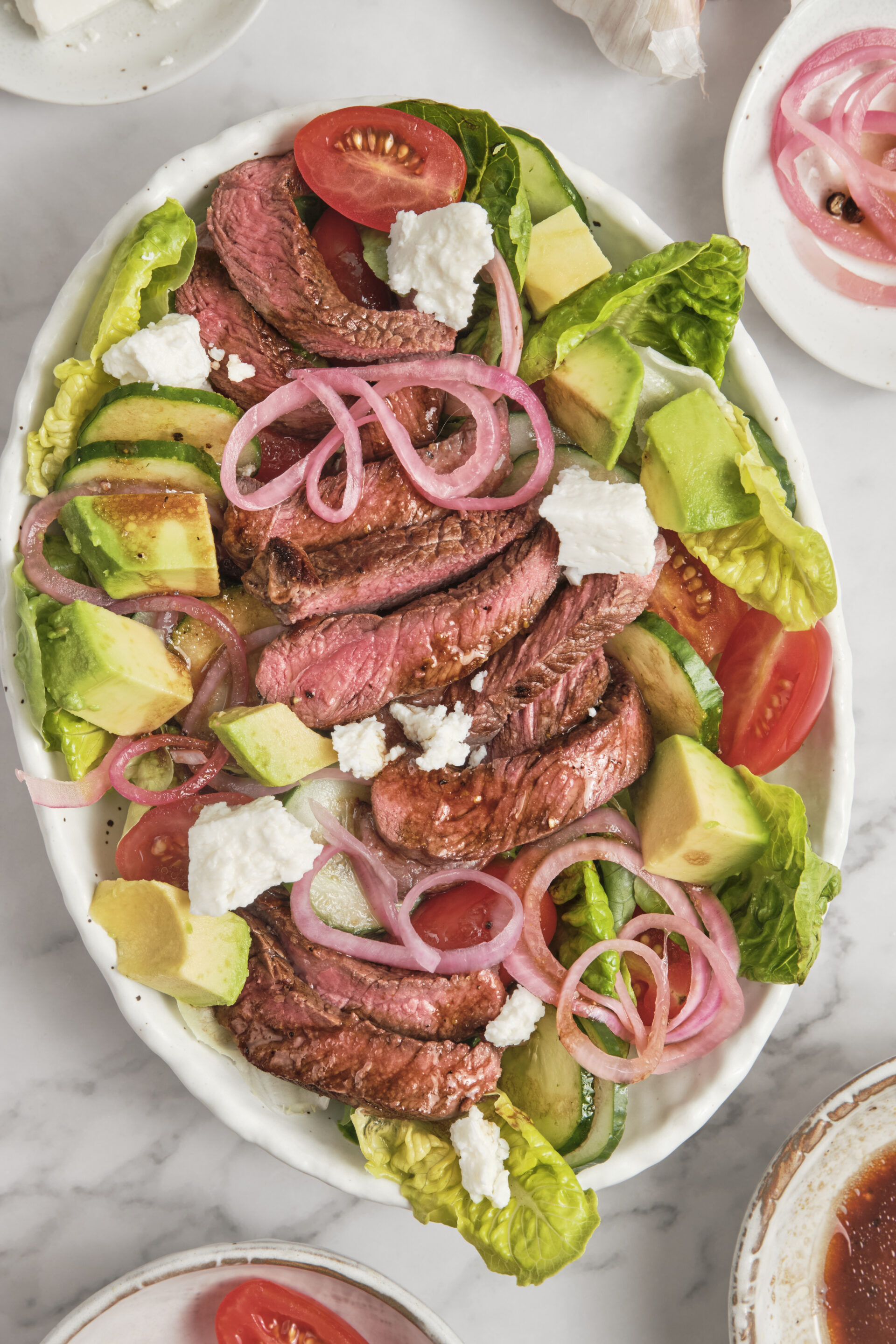 Juicy grilled steak served over fresh greens with avocado, cherry tomatoes, red onions, and creamy balsamic dressing in a healthy high-protein steak salad.