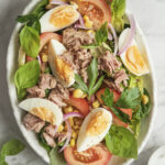 High-protein salad with hard-boiled eggs, tuna, corn, tomatoes, and red onion in a bowl.