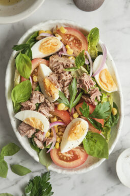 High-protein salad with hard-boiled eggs, tuna, corn, tomatoes, and red onion in a bowl.