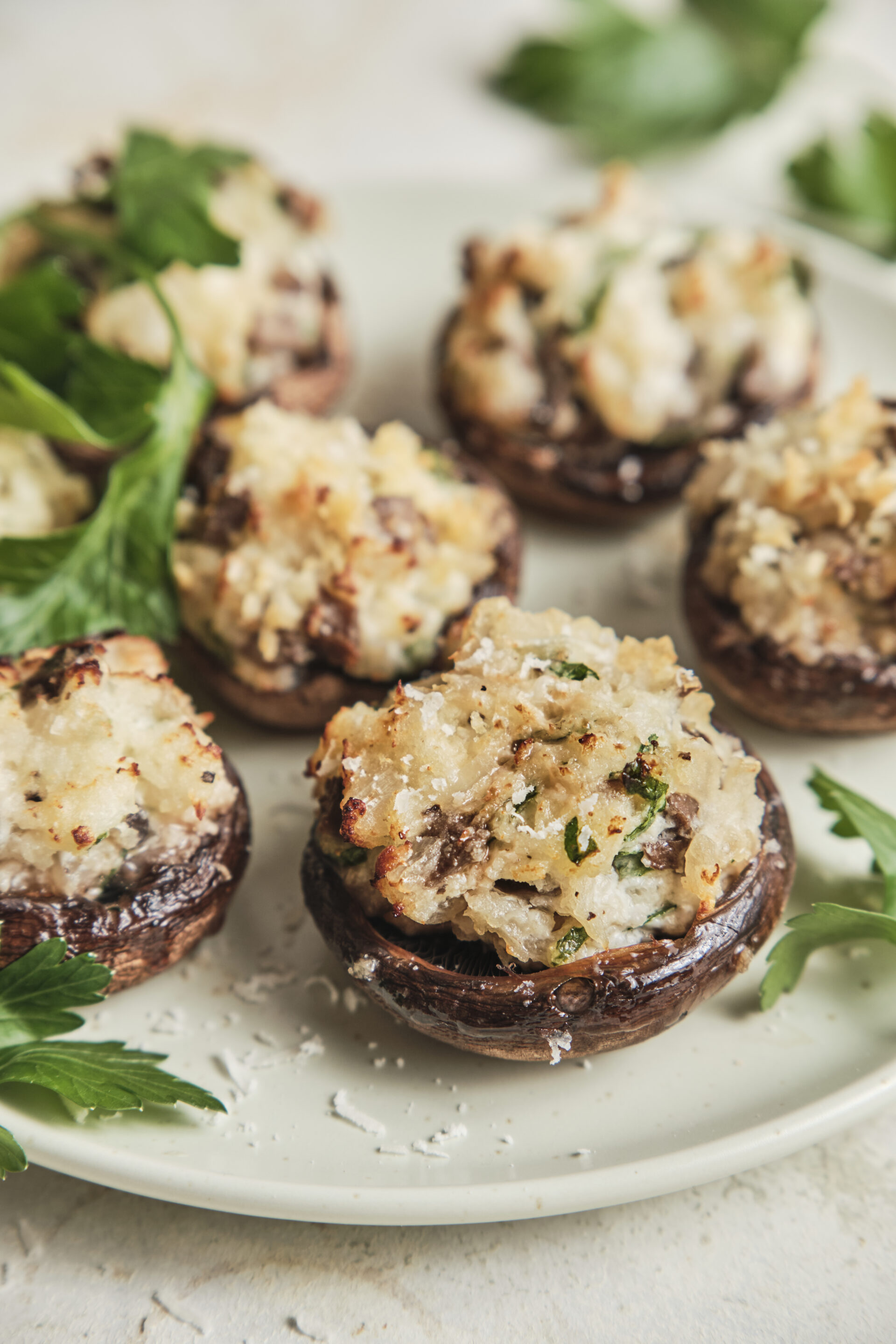 Golden baked stuffed mushrooms filled with a creamy cheese and herb mixture, topped with Parmesan and crispy breadcrumbs, served on a platter.